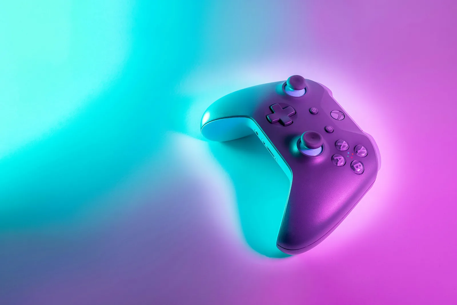 Ein kabelloser Xbox-Controller, angestrahlt von cyanfarbenem und magentafarbenem Neonlicht.